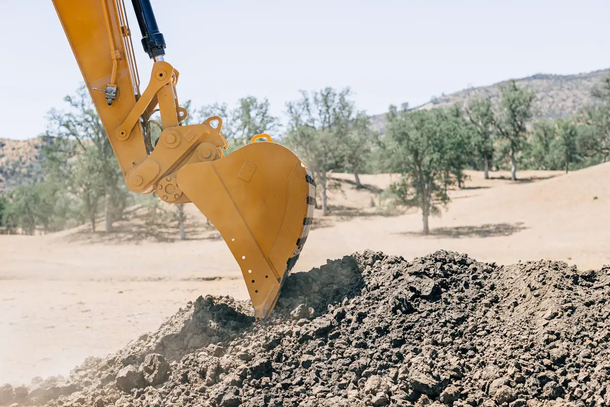 Excavator bucket digging French drain trench in Princeton TX yard